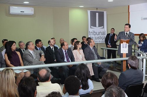 Sala de estar com parede bege, mesa de madeira e leque pendurado na parede