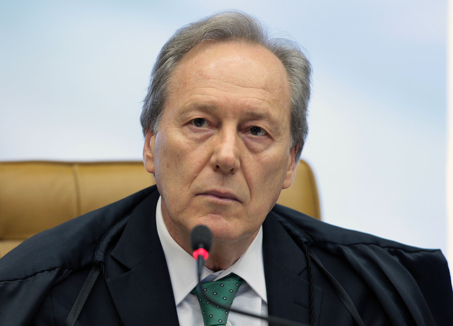 Sala de estar com poltronas cinzas, mesa de centro e adega ao fundo