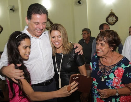 Mulher de maquiagem com um plástico vermelho em metade do rosto posando para foto em fundo verde 