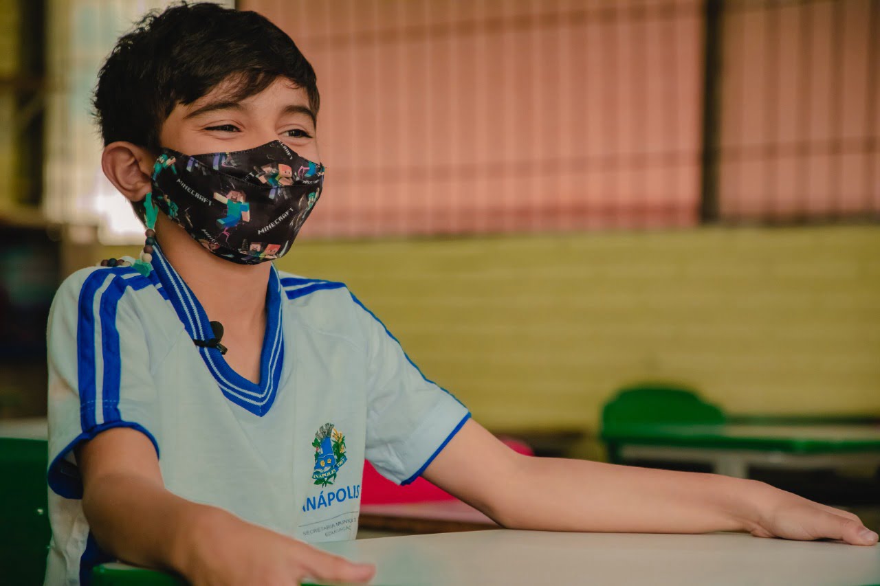 Mulher indiana sentada no sofá fazendo a pose de lótus: mãos apoiadas no colo, dedos dobrados e olhos fechados