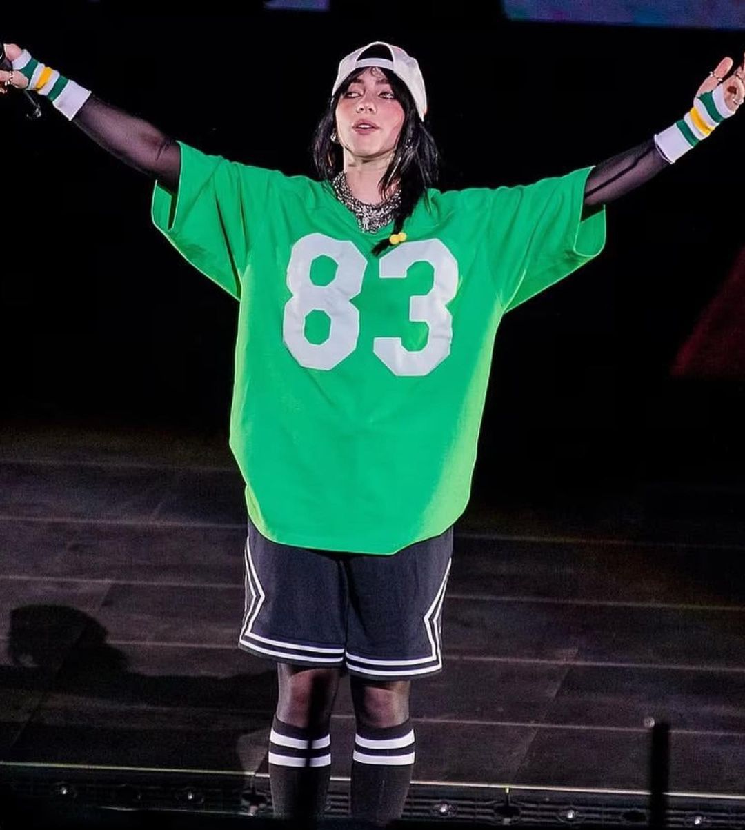 Mulher sorrindo e segurando copo com água em uma mão e comprimidos na outra