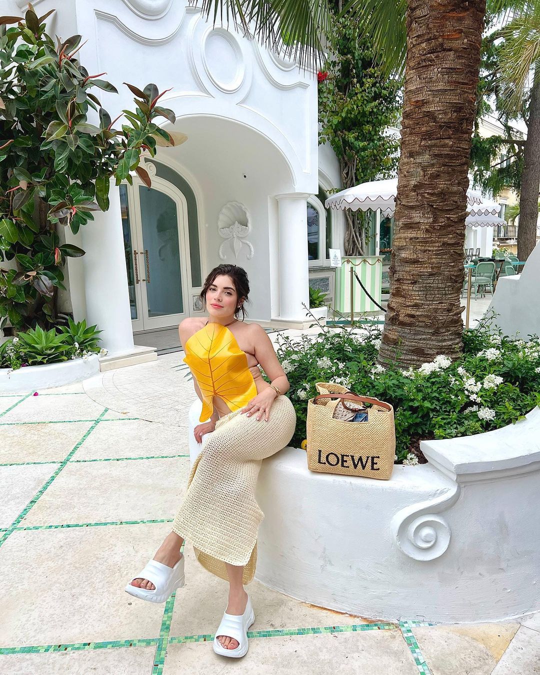 Chá de maçã com canela em xícara transparente, com pedaço da fruta e canela em pau; no fundo, há paus de canela e maçãs cortadas