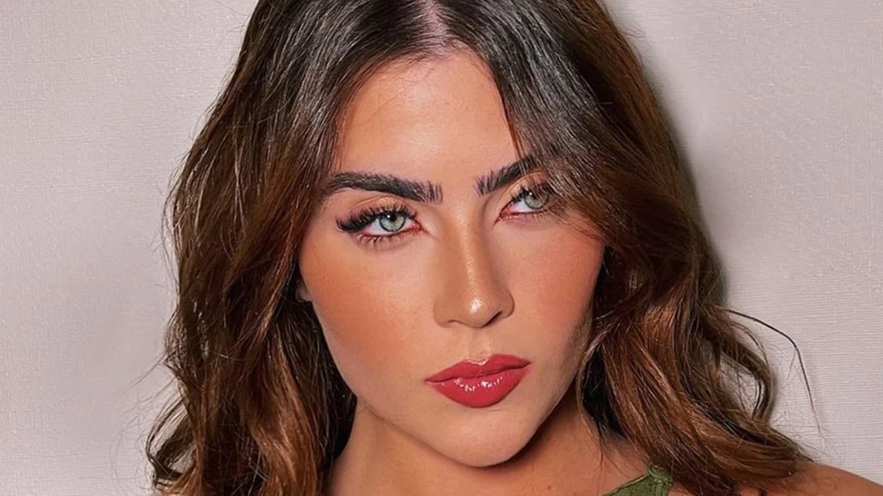 Mulher em uma cozinha cozinhando ao lado de um homem sorrindo ao seu lado tomando suco