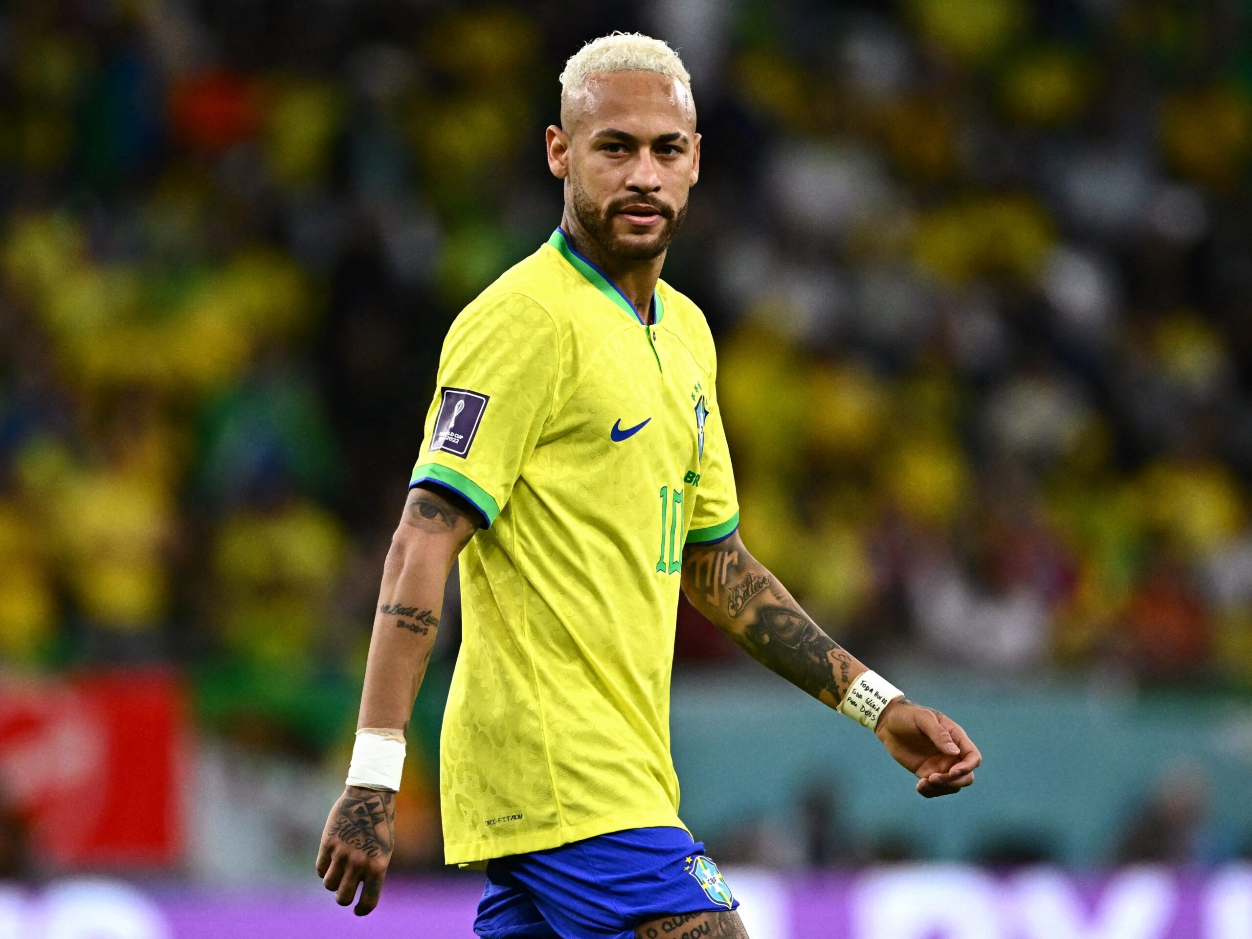 Sala de jantar com parede de madeira no estilo rústico, complementada por um lustre clássico e uma mesa de vidro