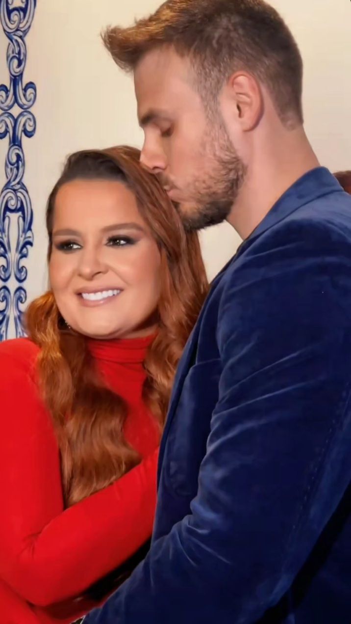 Mulher fantasiada de bruxa com vestido preto e chapéu pontiagudo segurando vassoura