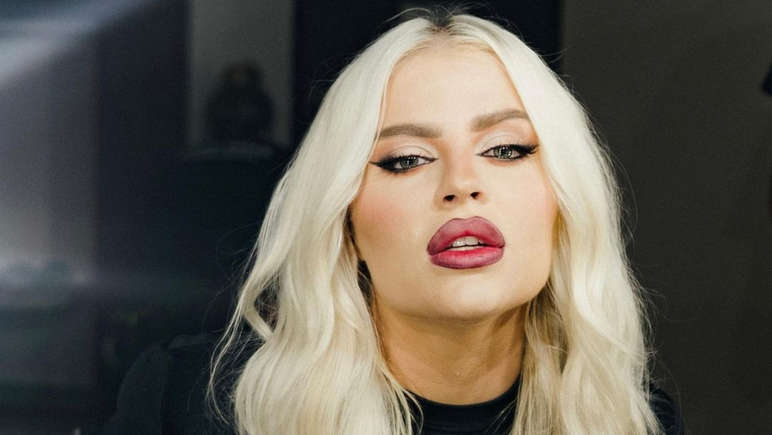 Dois gatos; um deles lambe o dedo de sua tutora