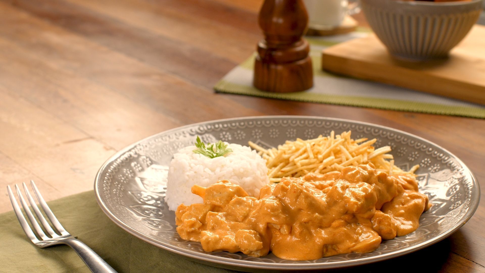 Mulher em uma cozinha confeitando um bolo com um saco de confeiteiro 