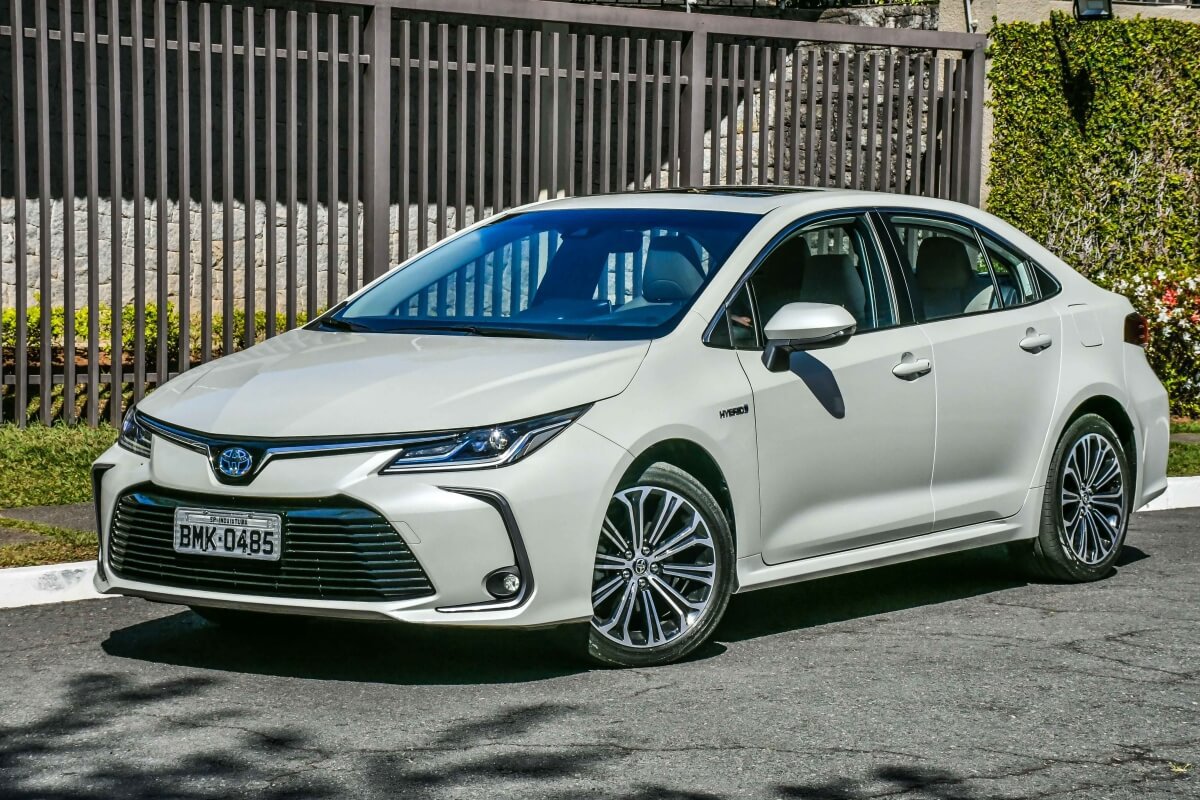 Atriz em frente a uma porta, segurando uma bola e usando boné 