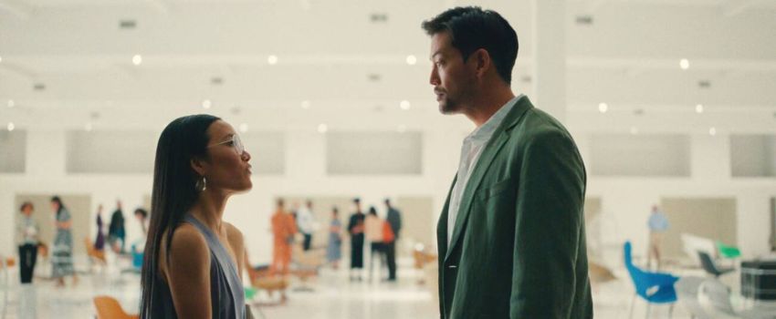 mulher abaixada no chão e abraçando cachorro branco e preto. ela está em sala de aeroporto com caixa de transporte ao lado