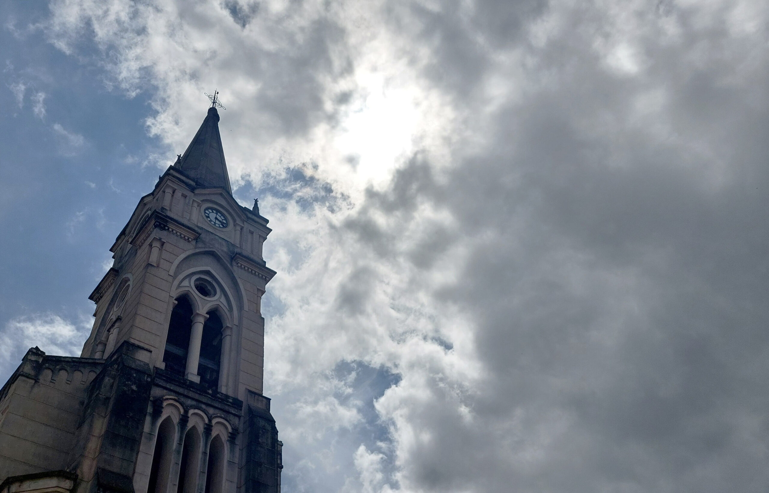 Mulher sentada em cima de mesa vestida de vermelho e atrás há diversos troféus 