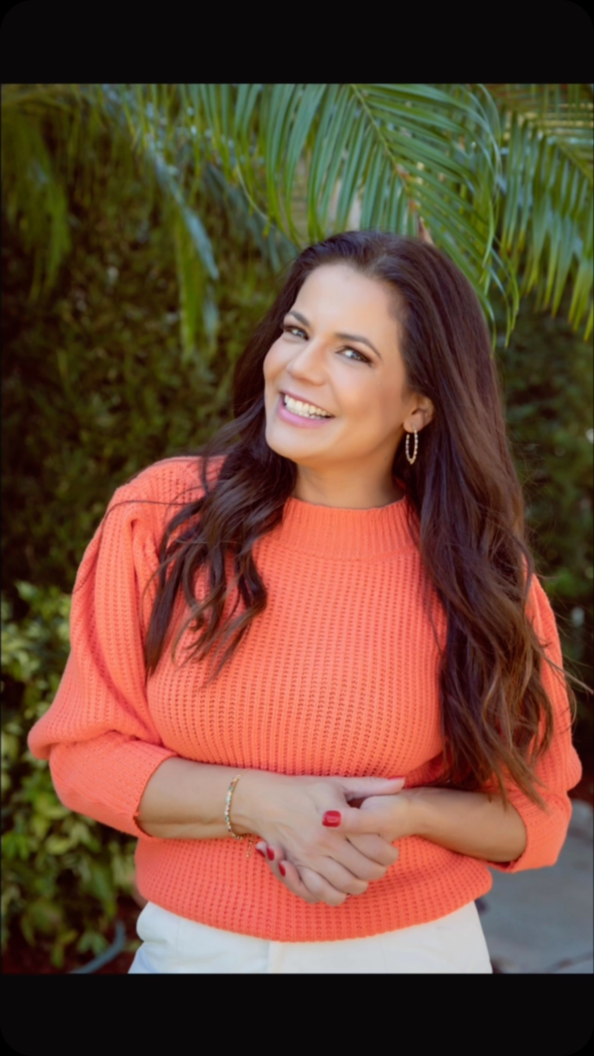 jovem de camiseta branca, sentada e escrevendo. notebook aberta à frente dela na mesa