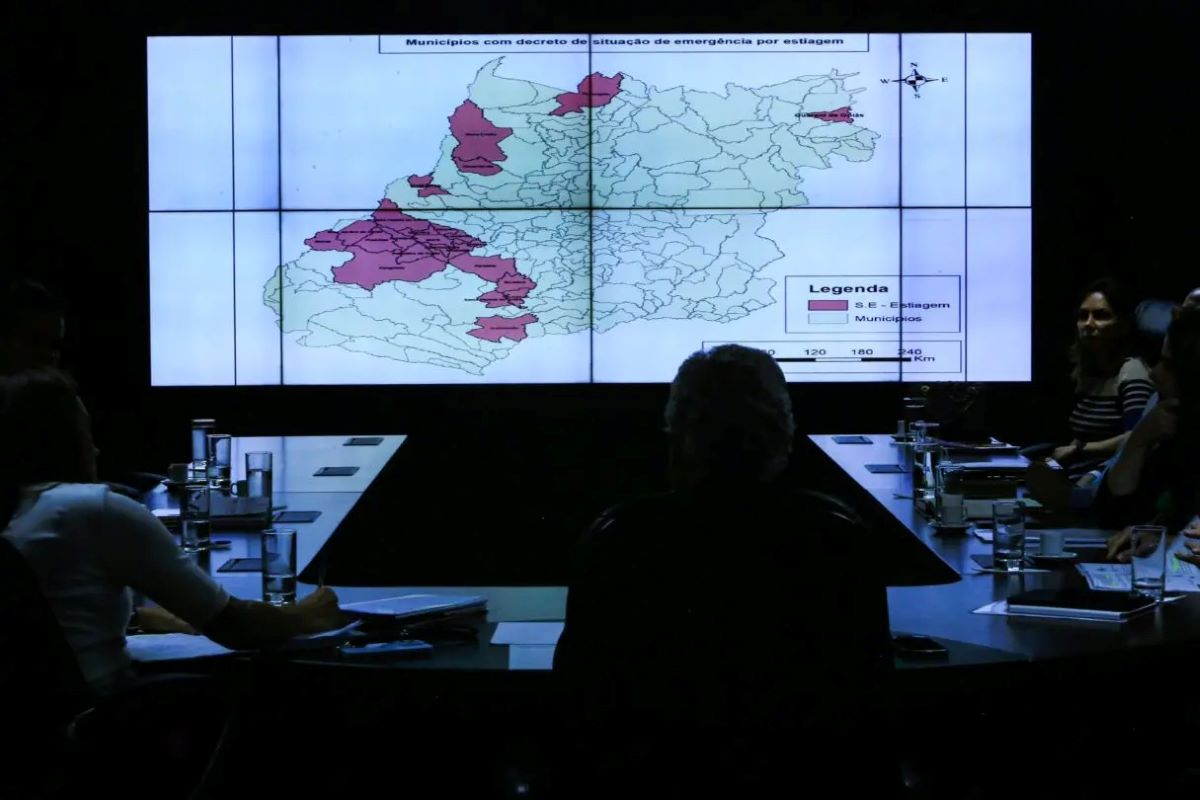 Imagem de duas mulheres, uma loira de cabelo solto usando roupas pretas e brancas e uma calça jeans e a outra usando roupas sociais brancas e bege e com o cabelo curto preto