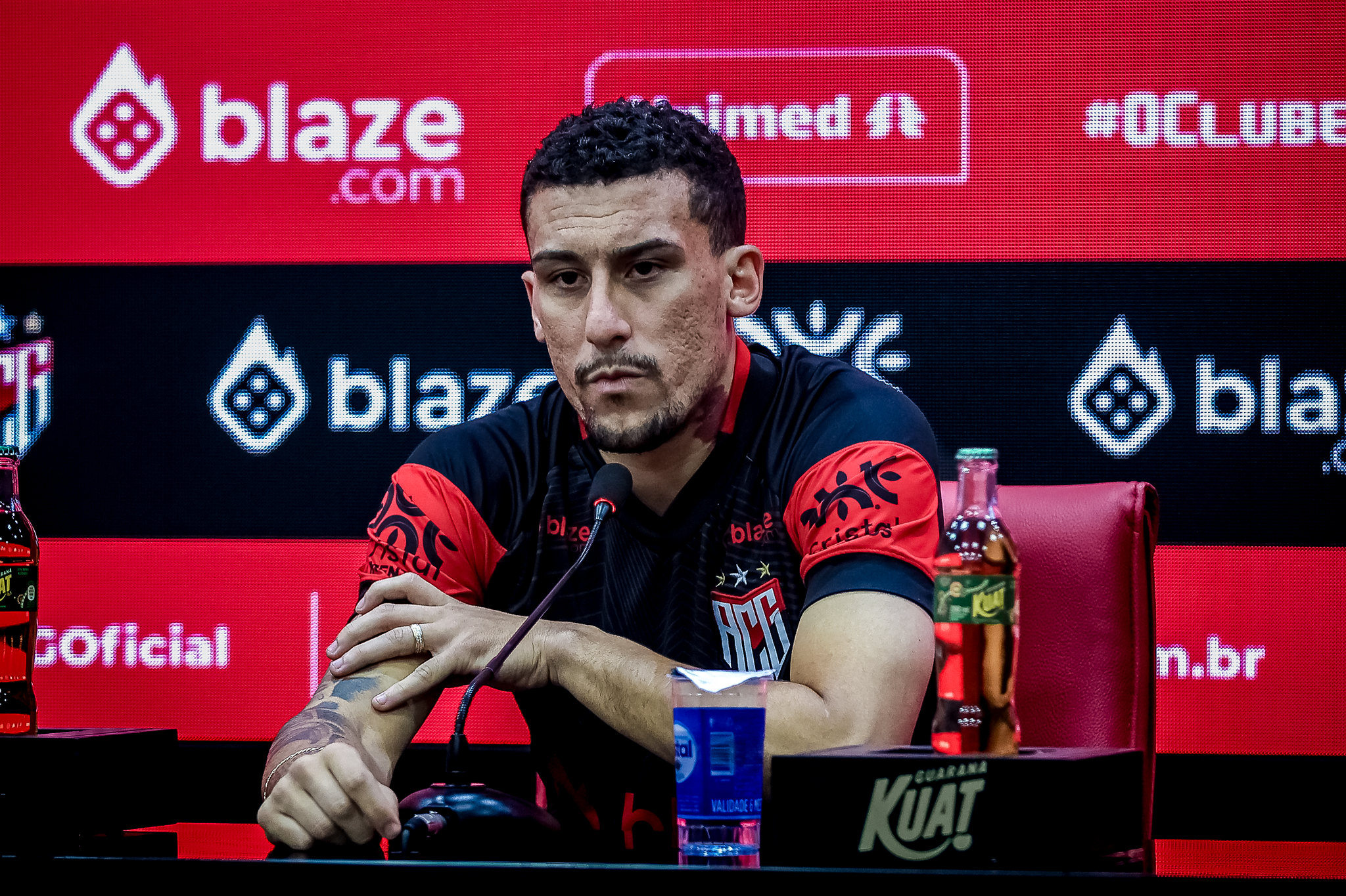 Ilustração do signo de Áries, em fundo alaranjado, com um carneiro claro de chifres verdes arqueados e expressão sorridente, sobre fundo estrelado