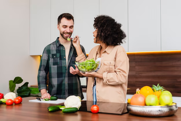 Jovem com cabelo liso, solto, usando camisa branca e segurando um repolho em cada mão próximo do rosto
