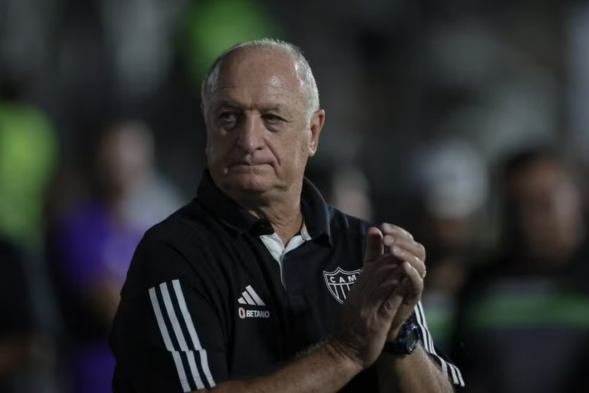 Creme de cenoura com cúrcuma servido em tigela de cerâmica em cima de mesa de madeira e com cenouras ao lado