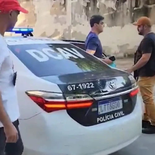 Ex-deputado é o que aparece sem boné, conduzido esta manhã para a delegacia por dois agentes Foto reprodução redes sociais