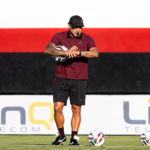 Treinador em Campo com Bolas de Futebol